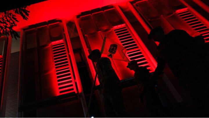 Craig Chandler | University Communication and Marketing Army ROTC cadets carry their guidon past the red-lighted Schorr Center as they head into the stadium.